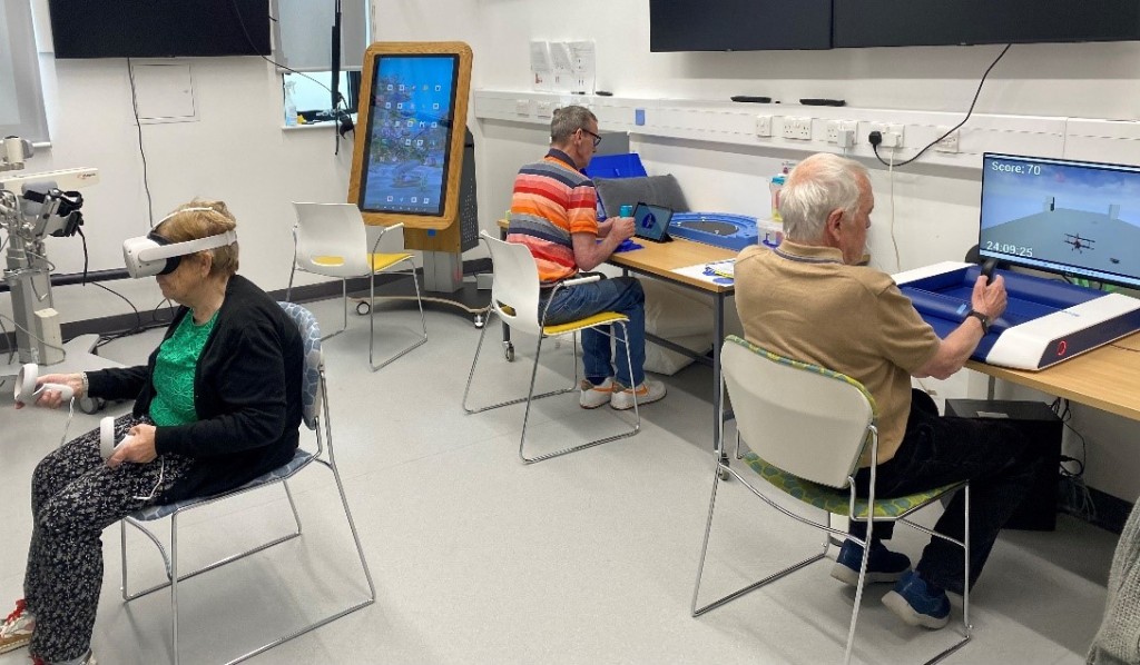 picture of three service users in a technology lab playing different consoles.